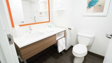 Une salle de bain moderne avec un lavabo blanc, un meuble-lavabo en bois, des toilettes blanches et un grand miroir avec un cadre orange.