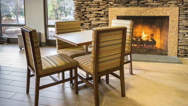 A restaurant with stone walls, a fireplace, and a television screen. - Hampton Inn Clarks Summit (Clarks Summit)