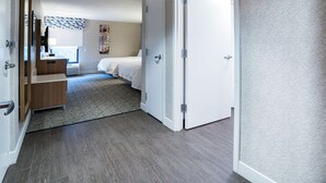 A hotel room with a wooden desk, a bed, and a small sitting area. - Hampton Inn Clarks Summit (Clarks Summit)