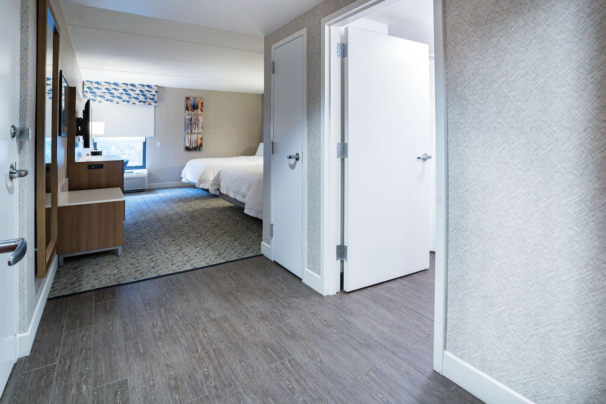A hotel room with a wooden desk, a bed, and a small sitting area.