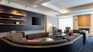 Un salon moderne avec un canapé aux lignes courbes, un téléviseur à écran plat fixé au mur, une cheminée et une table basse.