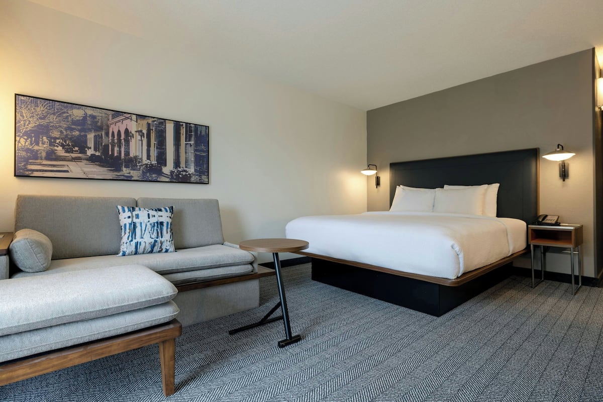 Ein Hotelzimmer mit einem Bett, einem Sofa, einem kleinen Tisch und einem Wandbild.