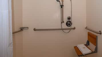 Zona de ducha con barra de apoyo, ducha de mano y toallero.