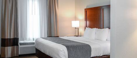 Une chambre d’hôtel avec un grand lit, une lampe de chevet et une fenêtre avec des rideaux.