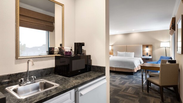 Ein Hotelzimmer mit Küchenzeile, einschließlich Spüle, Mikrowelle und Esstisch mit Stühlen.
