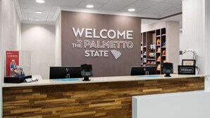 Ein Empfangsschalter mit einem Schild, auf dem 'Welcome to the Palmetto State' steht, eine Holztischplatte und eine Minibar.