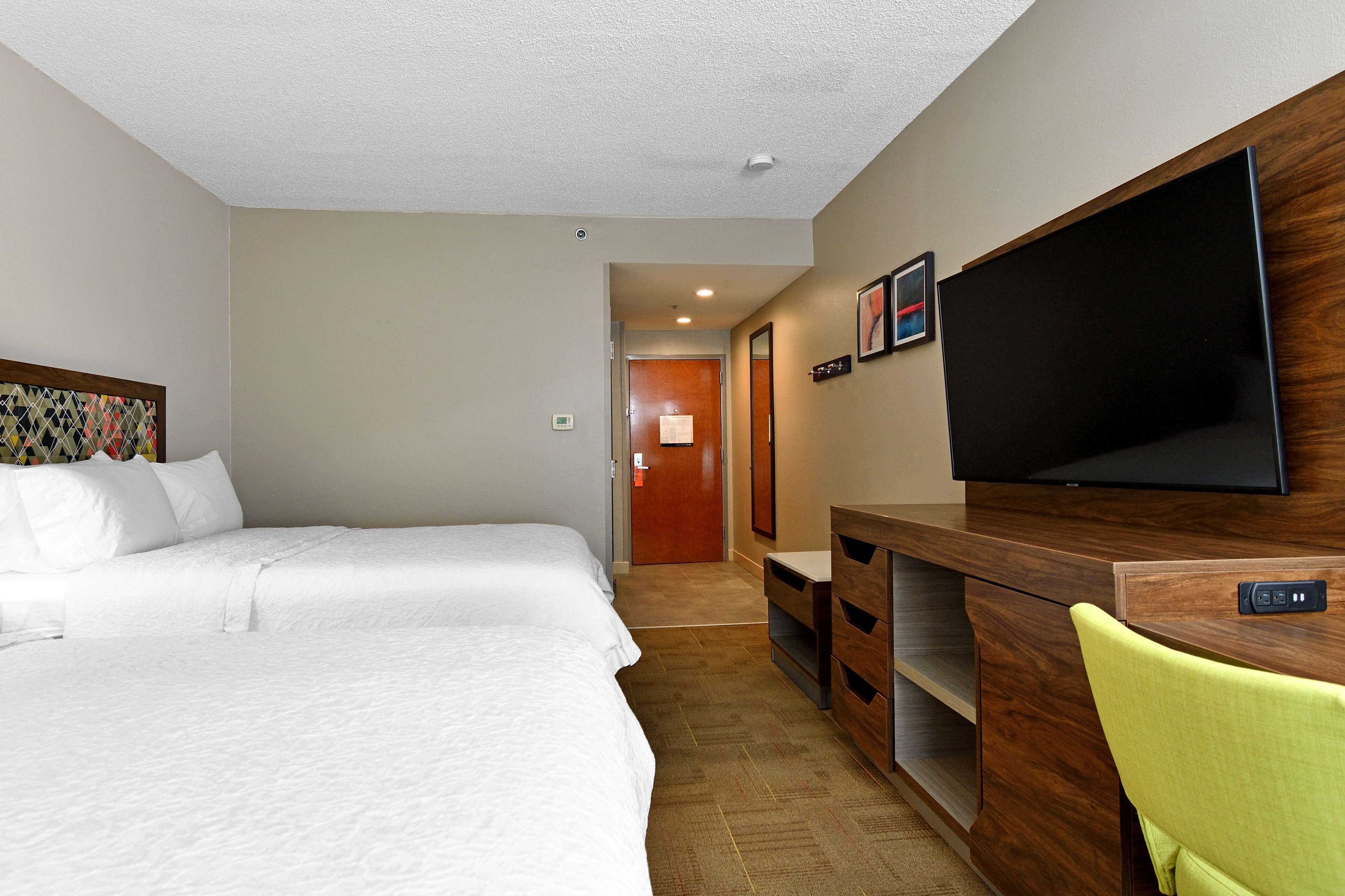 Une chambre d’hôtel avec deux lits, une télévision, un bureau et une chaise.