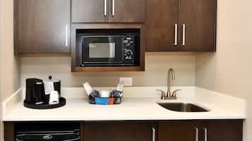 A compact kitchen with a microwave, coffee maker, and a sink.
