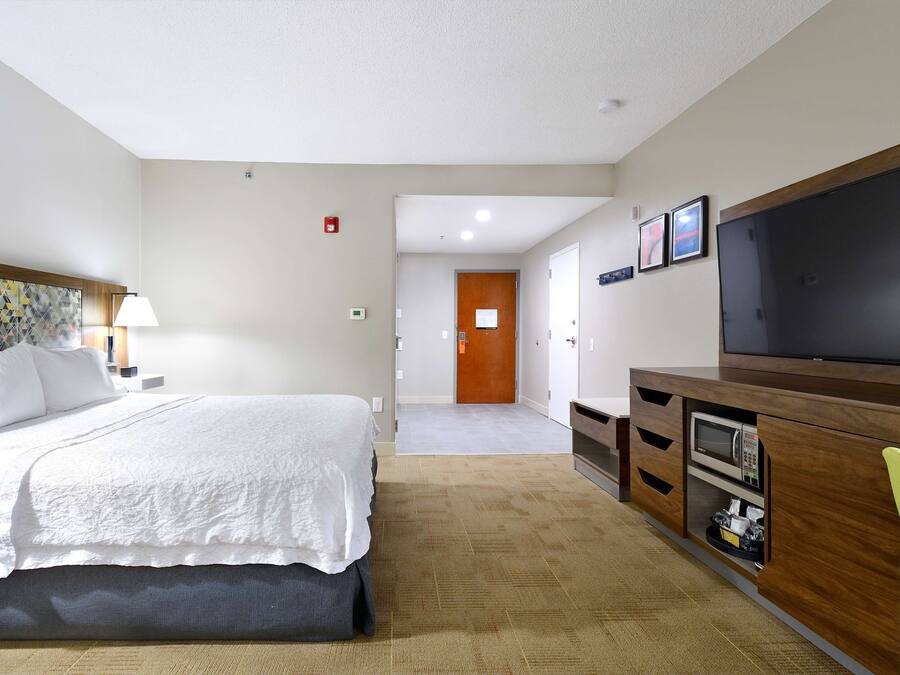 Hotellihuone, jossa on sänky, televisio, mikroaaltouuni ja työpöytä.