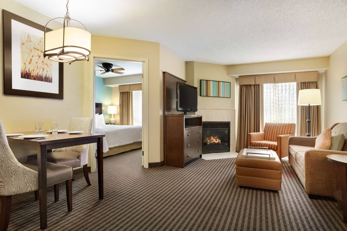 Ein Hotelzimmer mit Esstisch, Stühlen, einer Couch, einem Fernseher, einem Kamin und einem Deckenventilator.