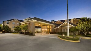 Entrada de un hotel con un corredor cubierto, varias ventanas e izquerdadera.