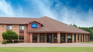 A Baymont Inn & Suites with a brick facade, large windows, and a covered outdoor area. - Baymont by Wyndham Enid (Enid)