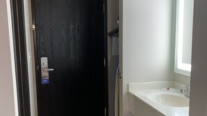 A bathroom with a white sink, a mirror, and a black door. - Baymont by Wyndham Enid (Enid)