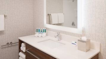 A modern bathroom with a white vanity, a large mirror, and a shower area.