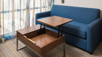 A room with a blue sofa, a wooden table with a metal frame, and a patterned curtain.
