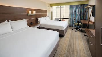 A hotel room with two beds, a desk, a chair, and a television.