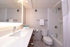 Une salle de bain moderne avec un grand miroir, un lavabo, des toilettes et une baignoire.