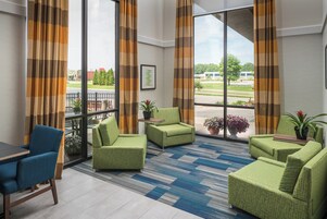 Un vestíbulo de hotel con zona de estar, ventanas amplias y vistas al exterior.