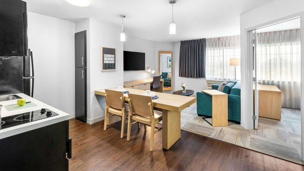 A modern kitchen with a dining area, a sofa, and a TV. - Sonesta Simply Suites Austin South (Austin)