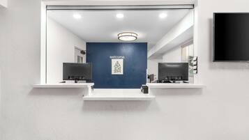A reception area with a blue wall and a welcome sign, two reception desks, and a mounted TV.