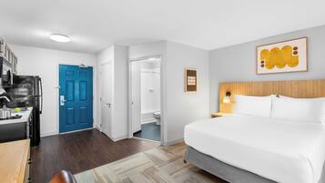 Une chambre d’hôtel avec un lit, un bureau et une kitchenette.