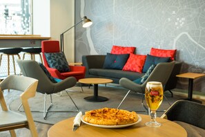 A dining area with a pizza on a table, a glass of beer, and modern furniture. - Holiday Inn Express Bristol City Centre by IHG (Bristol)