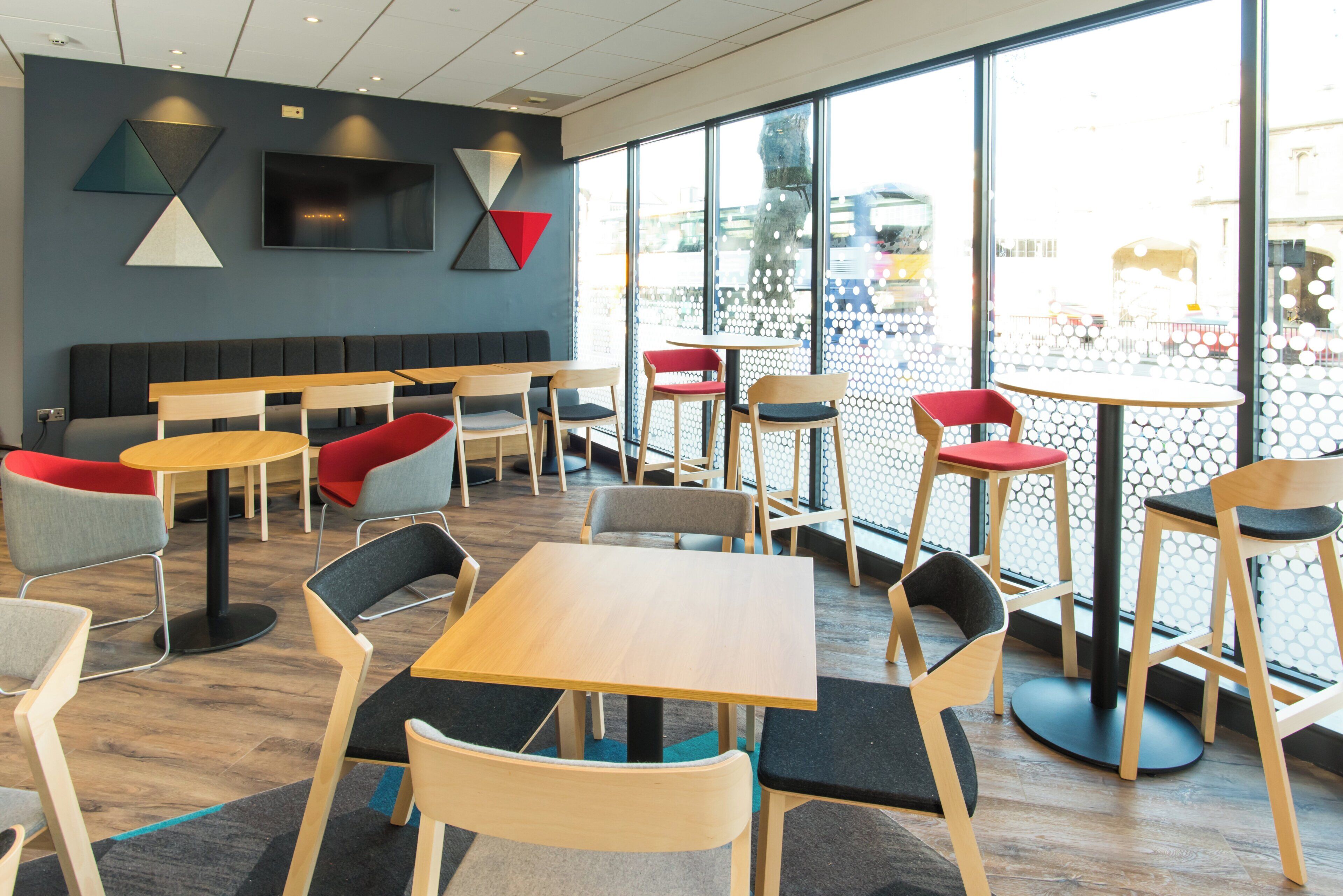 En modern caféinredning med olika typer av sittplatser, inklusive bord, stolar och en bänk.