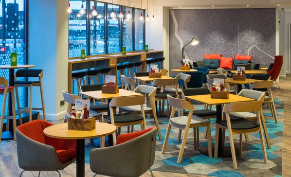 A modern restaurant with round tables and chairs, a large window with city views, and a map on the wall. - Holiday Inn Express Bristol City Centre by IHG (Bristol)