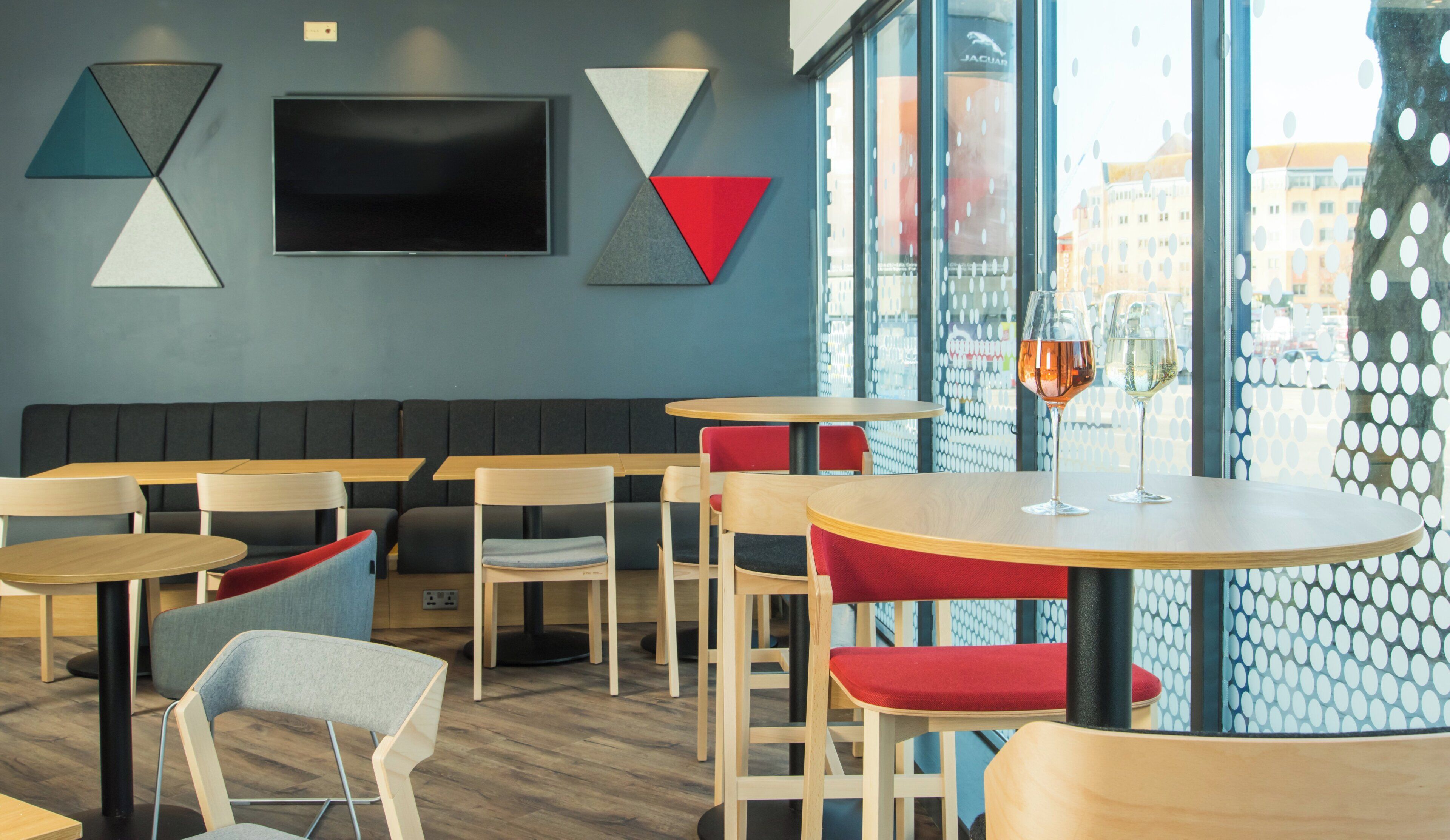 Un intérieur de restaurant moderne, avec des banquettes, des tables et une grande fenêtre offrant une vue panoramique.