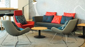 Uma área de estar moderna com um sofá, duas poltronas, uma mesa redonda pequena e um abajur.