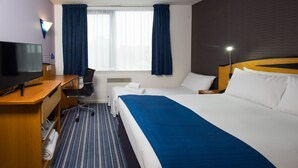 A hotel room with a bed, a desk with a TV, a chair, a window with curtains, and a bedside lamp. - Holiday Inn Express Bristol City Centre by IHG (Bristol)