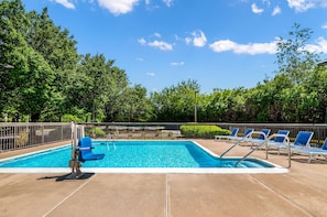 A swimming pool with blue chairs and a lifeguard stand.