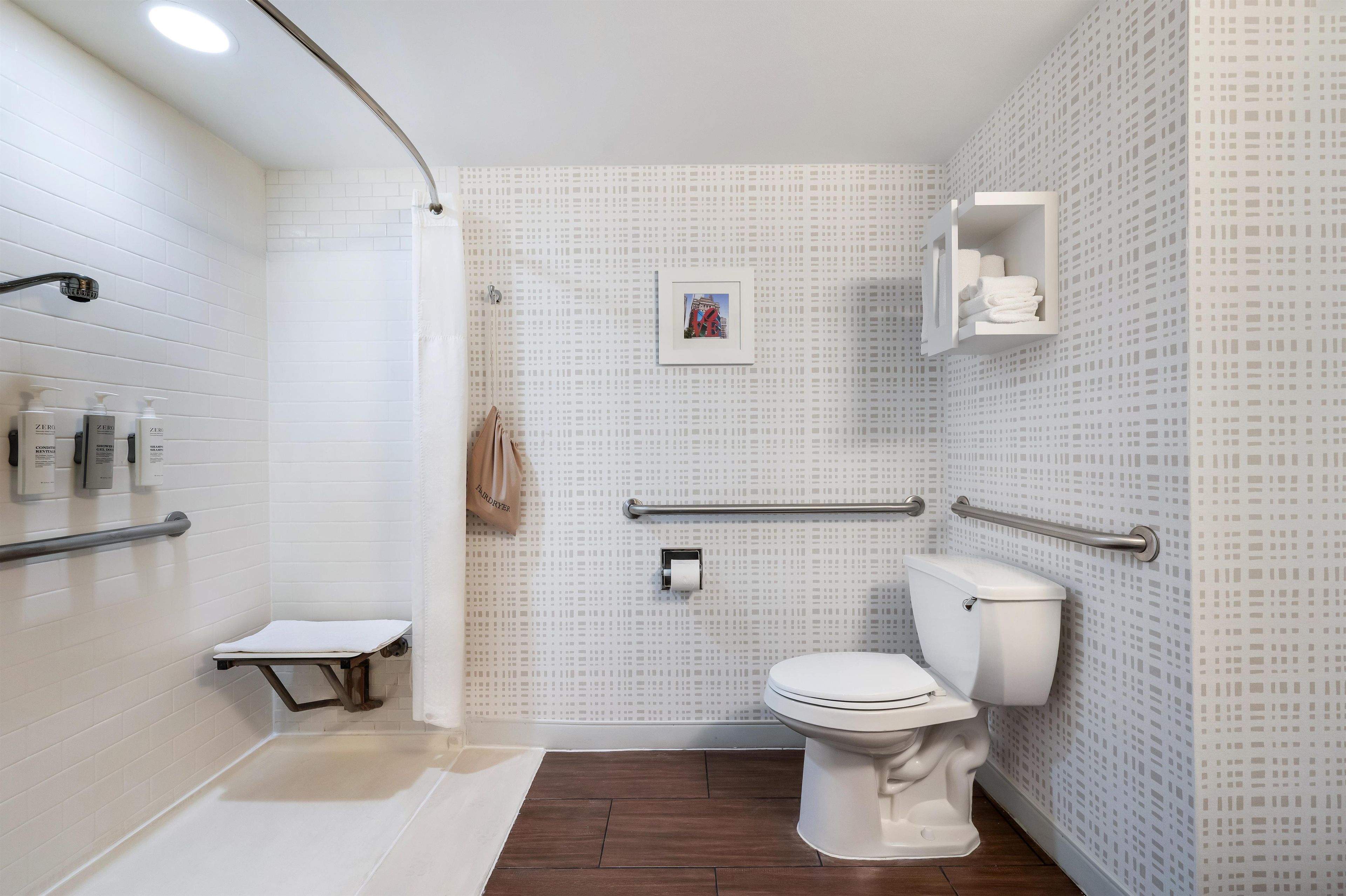 A modern bathroom with white tiled walls, a white toilet, a shower area, and a small bench.