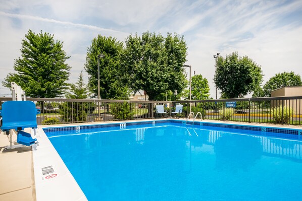 A swimming pool with a fenced area, lounge chairs, and a sign indicating a 25 people limit.