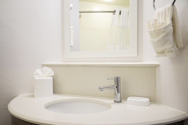 Un bagno con un lavandino bianco, uno specchio e un portasciugamani.