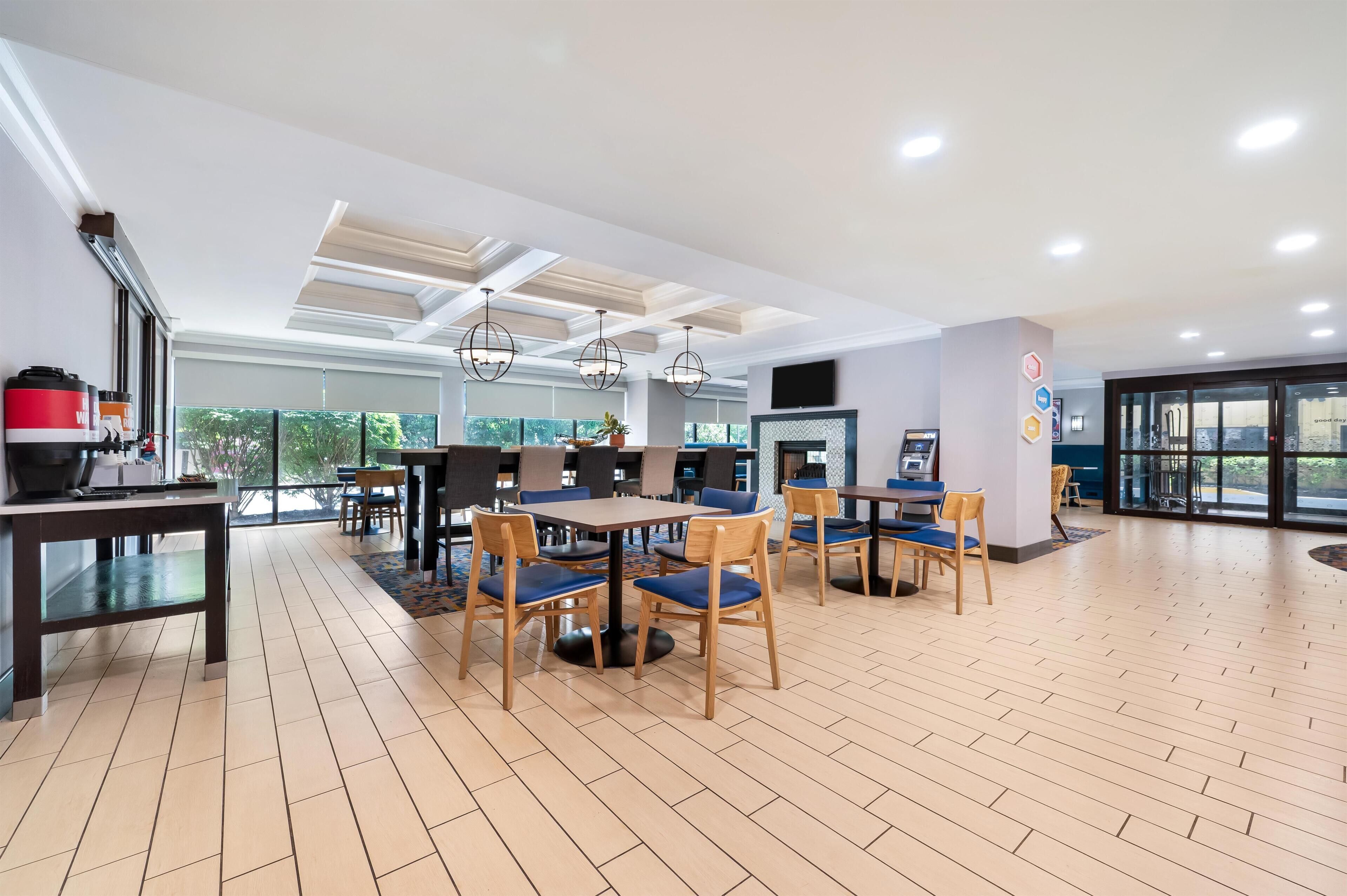 Un espace repas moderne avec des tables et des chaises, un comptoir de cuisine et une grande fenêtre offrant une belle vue.