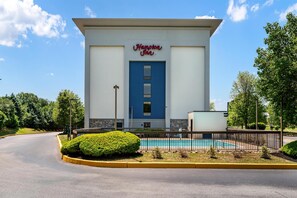 Un hôtel Hampton Inn avec une porte bleue, une piscine et un espace paysager aménagé.