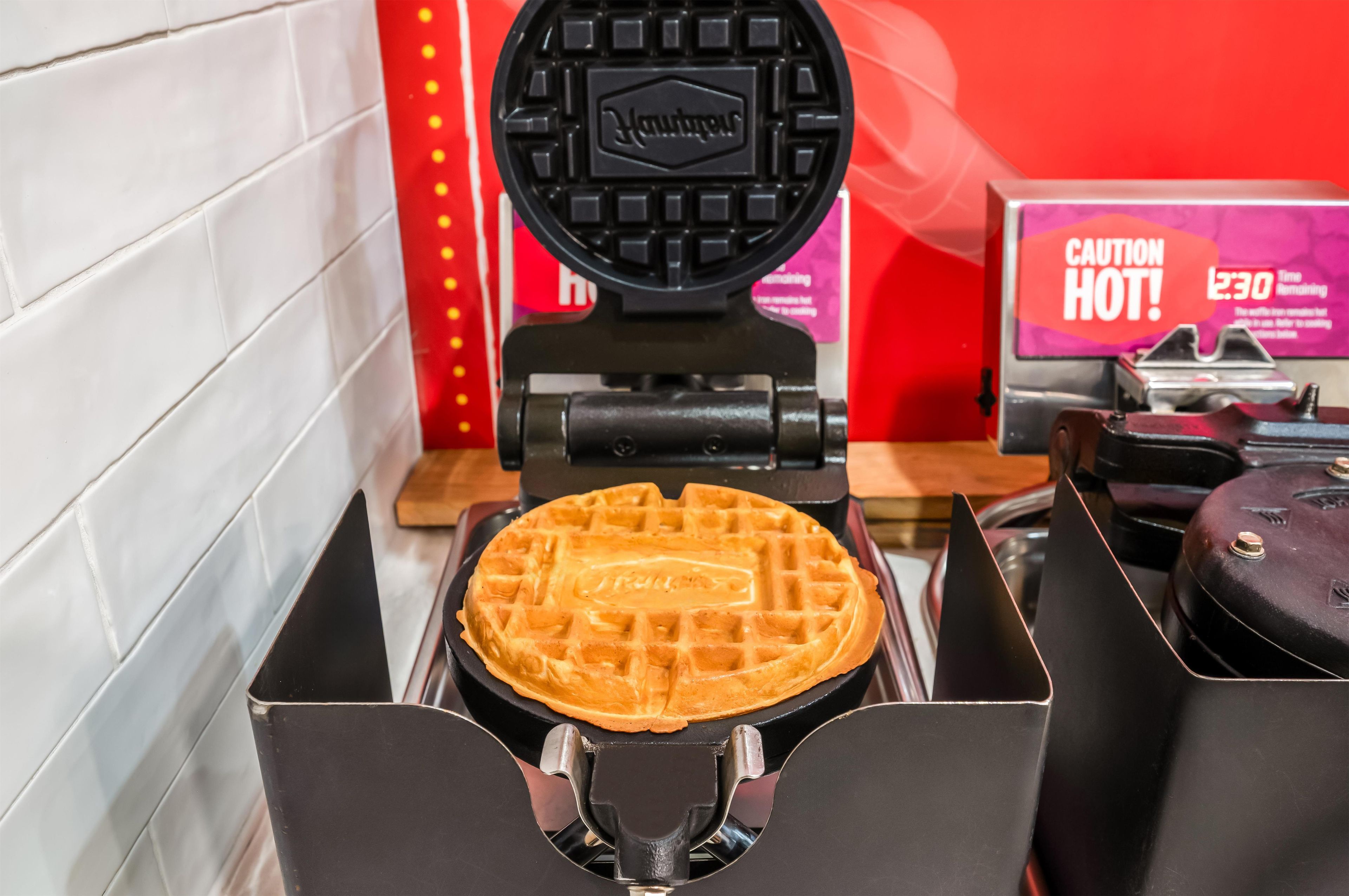 A waffle maker with a waffle inside, a caution sign, and a time limit sign.