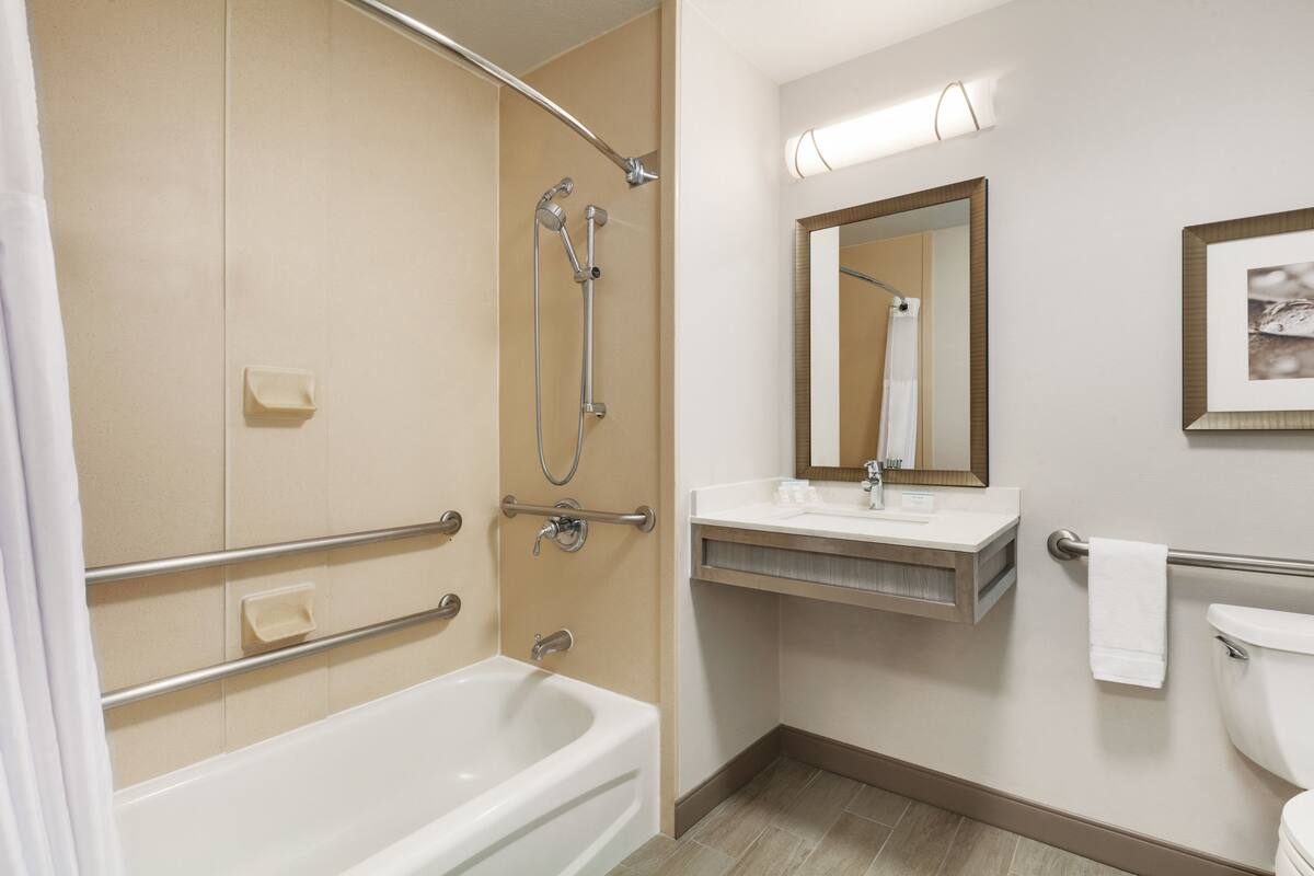 A bathroom with a bathtub, shower, vanity, and toilet.