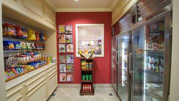 A kitchen with a red wall, a refrigerator, and shelves stocked with snacks and condiments.