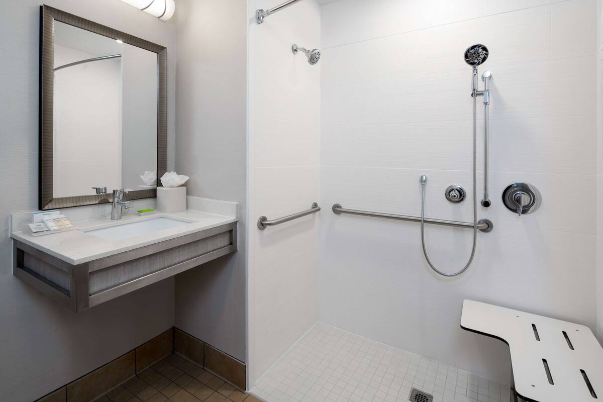 A modern bathroom with a sink, mirror, and shower.
