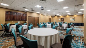 A conference room with round tables, teal chairs, and a carpeted floor.