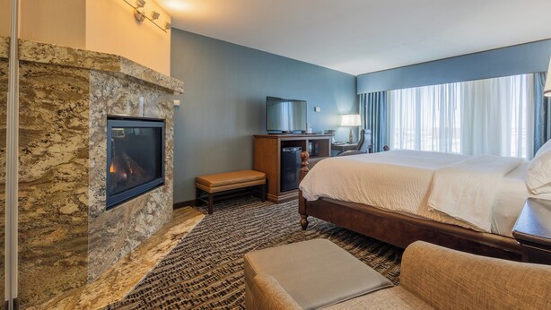 Una habitación de hotel con chimenea de piedra, una cama, un escritorio y un televisor.