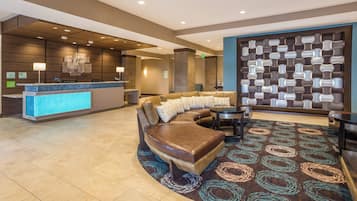 Eine Hotelhalle mit einer Rezeption, einer Sitzecke und einer Dekowand.