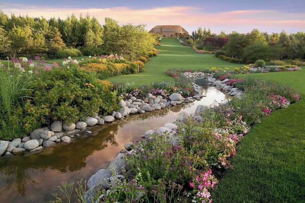 Un parcours de golf avec un étang, entouré d’une végétation luxuriante et de plantes en fleurs.