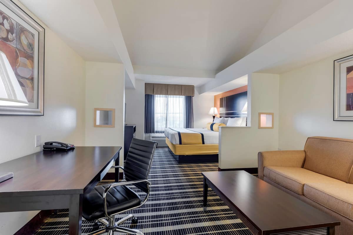 A hotel room with a bed, a desk with a telephone, a sofa, and a chair.