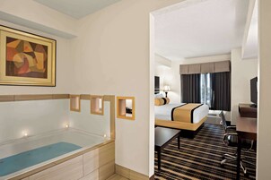 Una habitación de hotel con bañera, cama, escritorio y televisor.