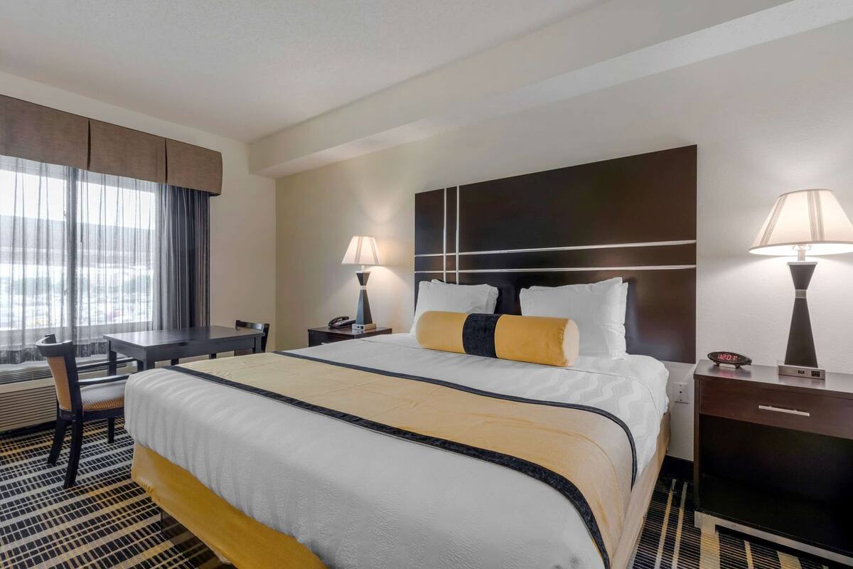 A hotel room with a bed, bedside tables, a desk, and a chair.