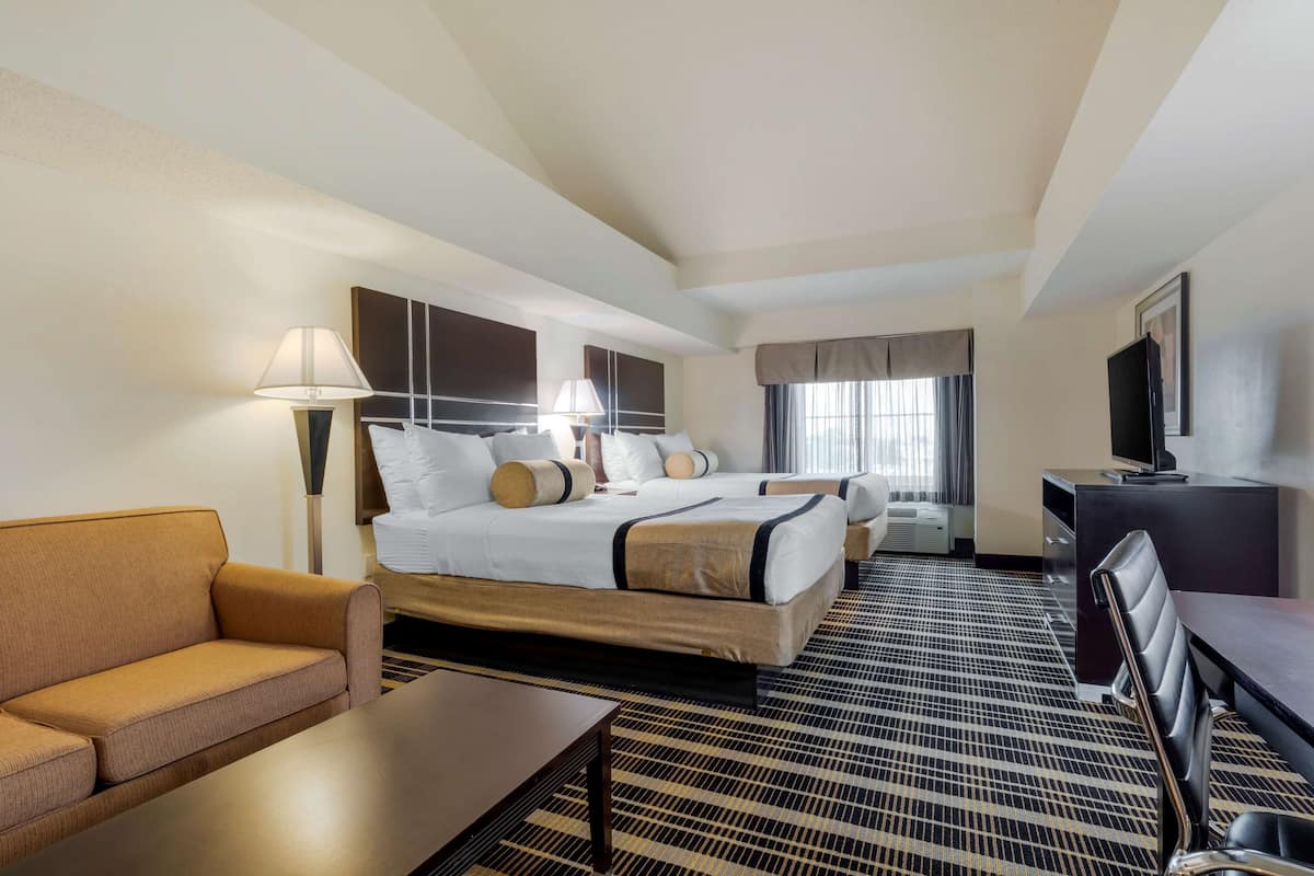A hotel room with a large bed, a sofa, a desk, and a TV.