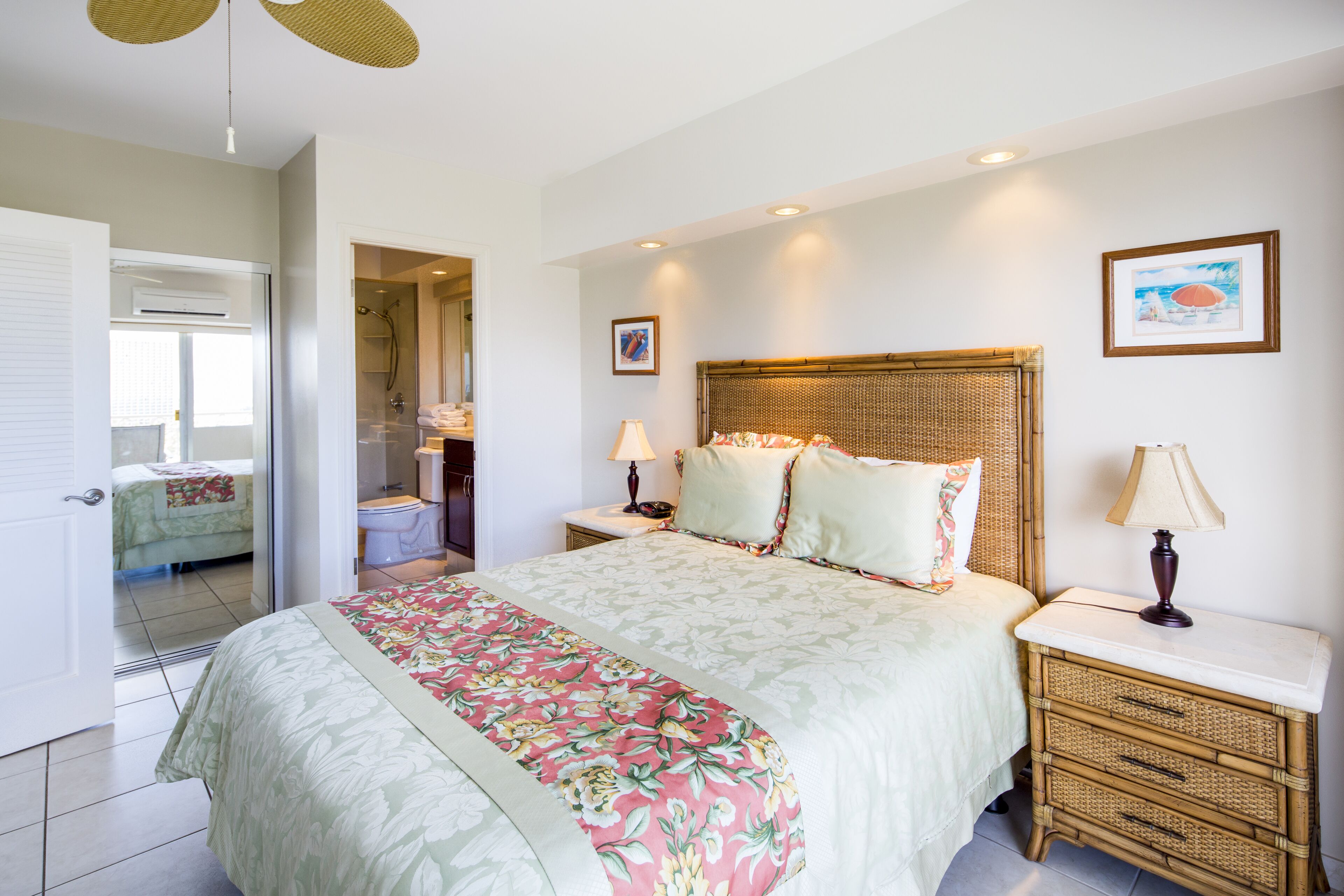 A neatly arranged bedroom with a bed, bedside tables, and a bathroom visible through an open door.